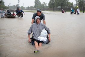 Man pushing another man in a wheelchair through the floodwaters of Hurricane Harvey