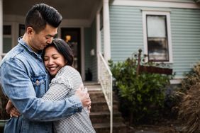Portrait of young couple hugging and smiling in front of their new home