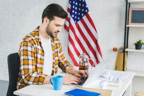 Man working on laptop with U.S. flag in the background