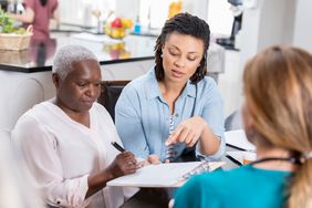 Mid adult woman helps her senior mother with medical paperwork.