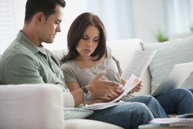 Young couple going over their financial budget to determine if they can live off of one income while sitting on their couch
