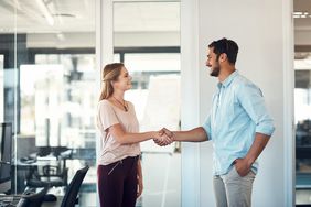 Shot of a businessman and businesswoman shaking hands in a modern office