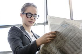 Businesswoman reading newspaper in office