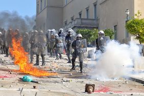 Riot police in Greece surrounded by flames and smoke