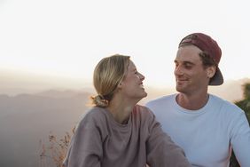 Happy young couple on a hiking trip having a break at sunrise