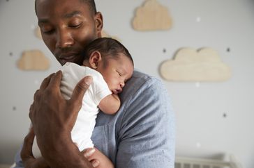 Father holding baby as it sleeps on his shoulder