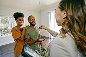Real estate agent handing house keys to a young couple in an empty living room