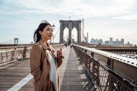 A woman stand on the Brooklyn Bridge.