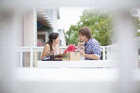 young married couple arguing about finances at a table on the balcony