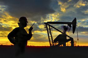 Oil field worker in front of oil rig