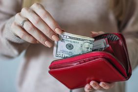Woman placing cash into a wallet for savings
