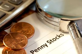 Pennies with calculator and magnifying glass representing penny stocks
