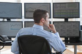 Day trader working with multiple computer screens in front of him