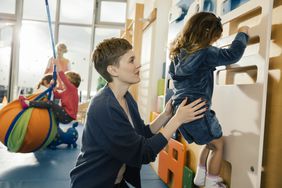 Pre-school childcare teacher helping little girl