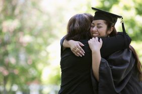 Mother hugging college graduate daughter