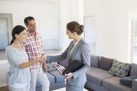 realtor and couple shaking hands in living room
