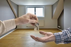 Realtor giving house key to buyer in empty room