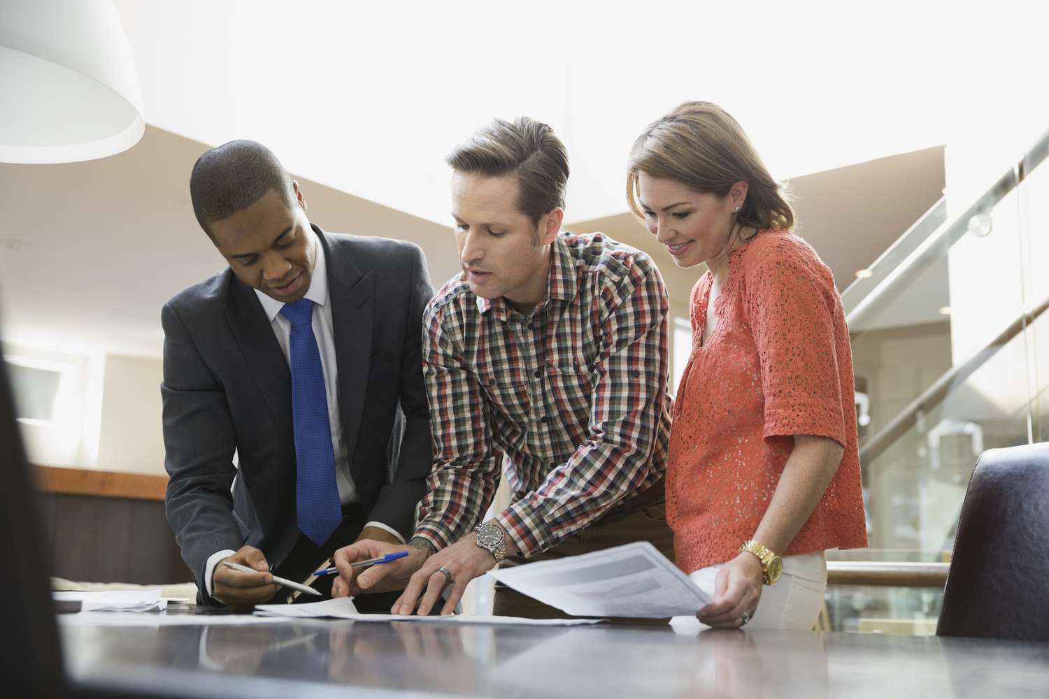 Couple gathered with an investment advisor looking at paperwork on a table