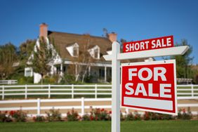Short Sale, House for Sale sign in front of fenced two-story hone