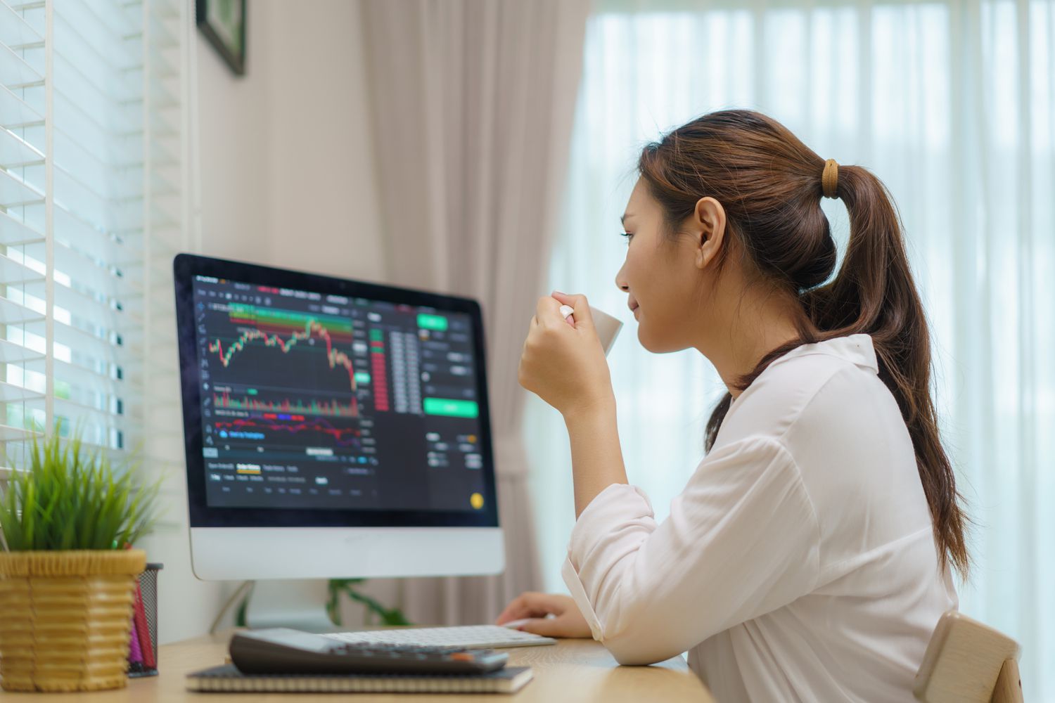 woman sitting at desk at home trading stocks or cryptocurrency