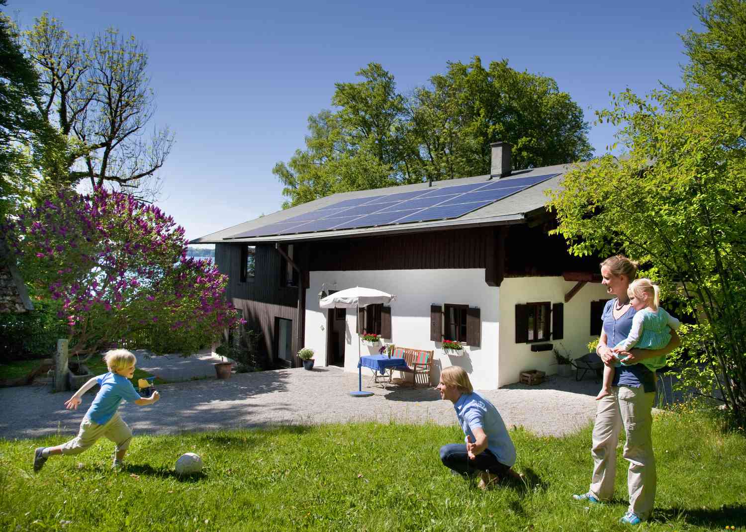 family playing outside in front of their home that has a solar panel system