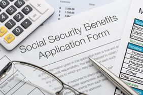 Social security benefits application form with a pen, glasses, calculator and documents.