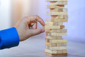 Hand removing block from Jenga game signifying planning, risk and strategy in business