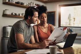 Couple at a laptop in a kitchen studying paperwork