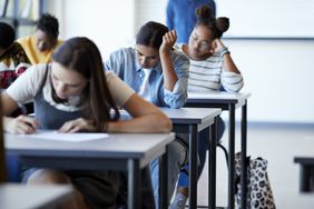 Three college-age students focus on exam in classroom
