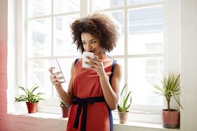 Woman drinking coffee and checking her phone