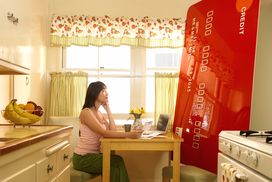 A woman looks at a huge credit card in her kitchen