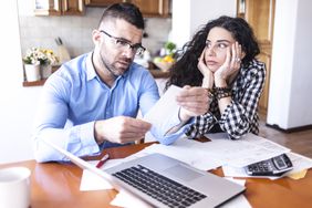 young couple looking at documents together at kitchen table